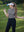 Model in light grey women's performance solid polo holding a golf club outdoors