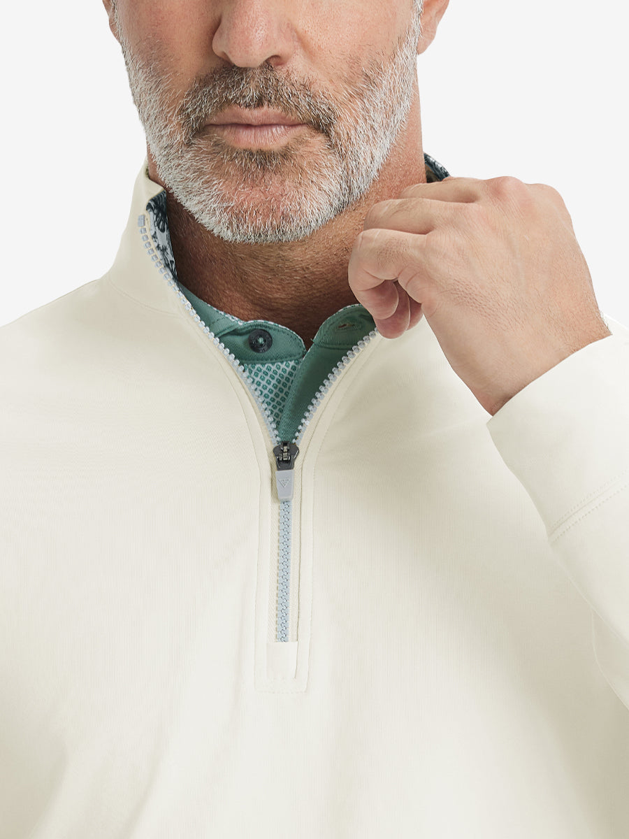 Close-up from nose to chest, showing collar and zipper detail of the cream golf pullover.