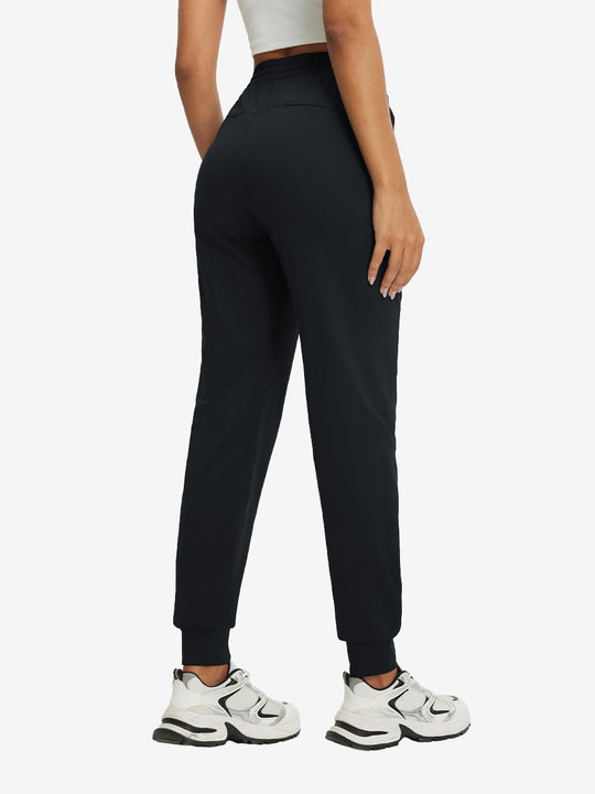 Back view of lightweight women's stretchy joggers sweatpants on model, shown in black.
