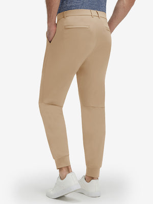 Back lower body shot of model wearing light khaki flat front golf joggers pants with belt loops