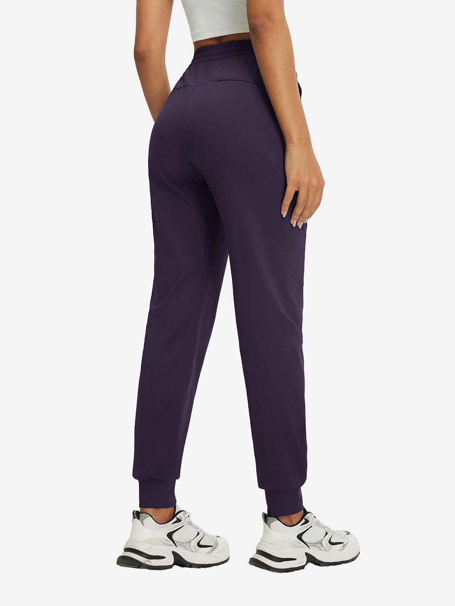 Back view of lightweight women's stretchy joggers sweatpants on model, shown in dark purple.