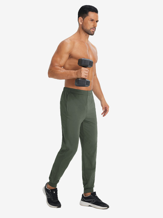 Model holding tennis racket wearing lightweight traning track pants in olive green.