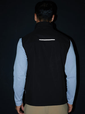 Model back half-body shot showcasing sleeveless softshell fleece outdoor vests with 6 pockets in black