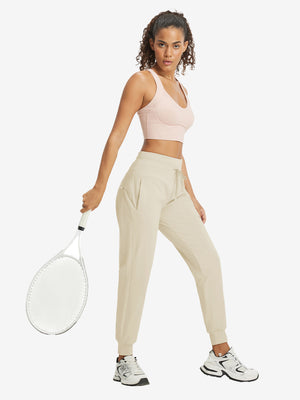 Full-body front view of model wearing women's stretch fleece lined water resistant joggers in light khaki.