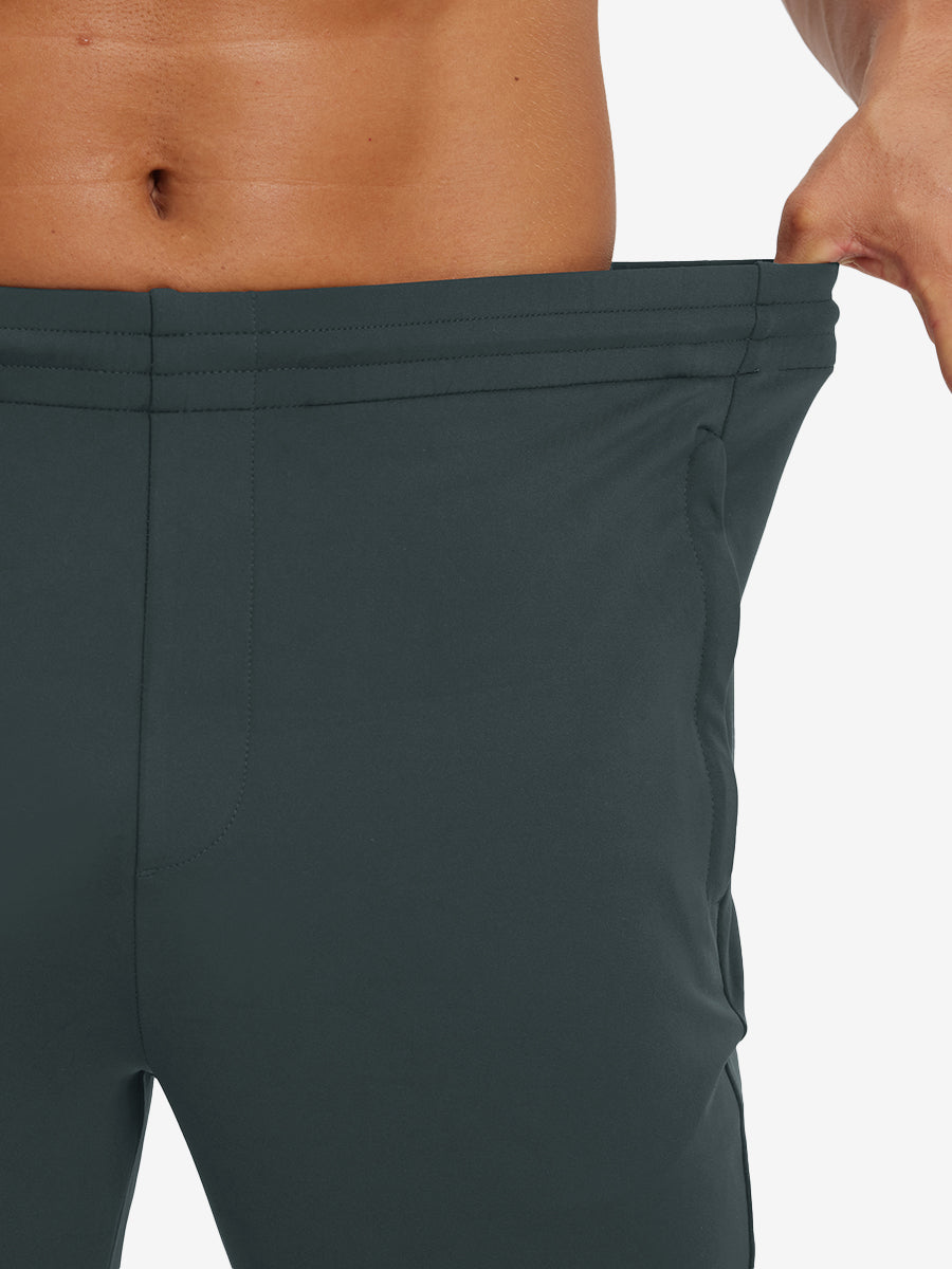Model stretching waistband to show fit of lightweight traning track pants in dark grey.