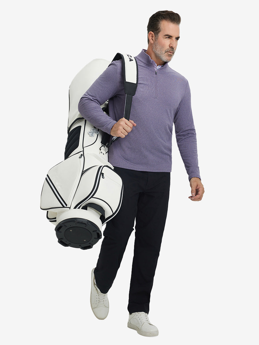 Model carrying golf bag on back, wearing casual fleece lined quarter zip pullover in purple, full-body.