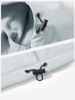 Close-up of zipper and button details on reflective hooded softshell jacket in light gray.