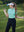 Model in blue light women's performance solid polo holding a golf club outdoors