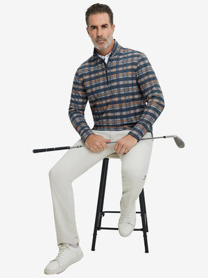 Full-body shot of model holding golf club, dressed in full print quarter zip pullover in blue/white/yellow plaid.