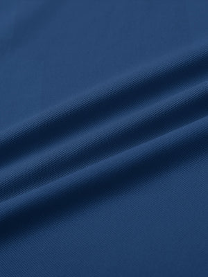 Close-up of blue long sleeve solid jersey polo fabric texture showing soft knit and smooth finish details.