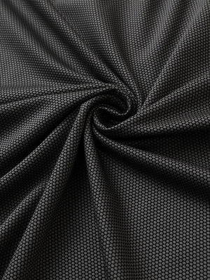 Close-up of black performance ananas jacquard polo fabric showing refined texture.