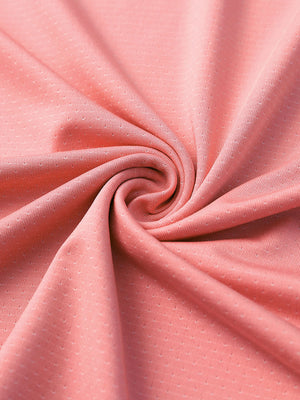 Close-up of peach pink 4 way stretch jacquard polo fabric texture highlighting intricate woven pattern and elasticity.