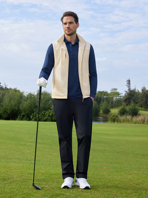 A model holding a golf club is photographed in a full-body shot, wearing a khaki windproof fleece reversible golf vest.