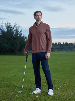 Model leaning on a golf club on course, styled in quarter zip melange pullover with relaxed brick heather tone