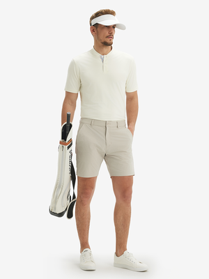 Full-body front view: model in cream moisture-wicking short sleeve henley shirt holding golf bag.